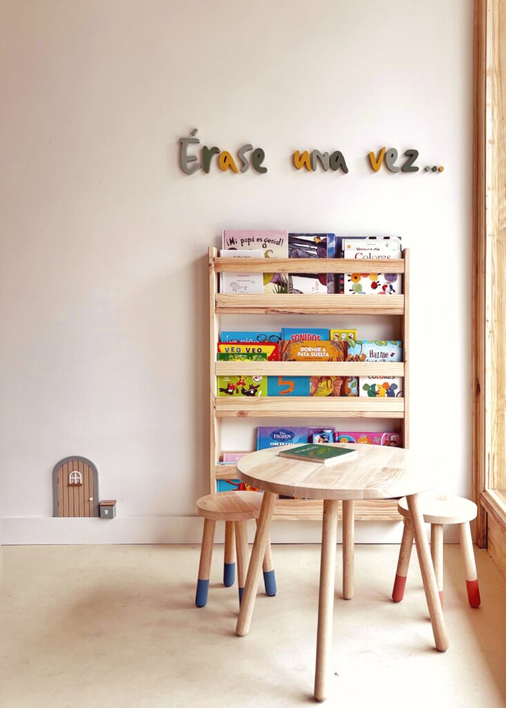 Rincón de lectura infantil con estantería de libros y mesa de madera