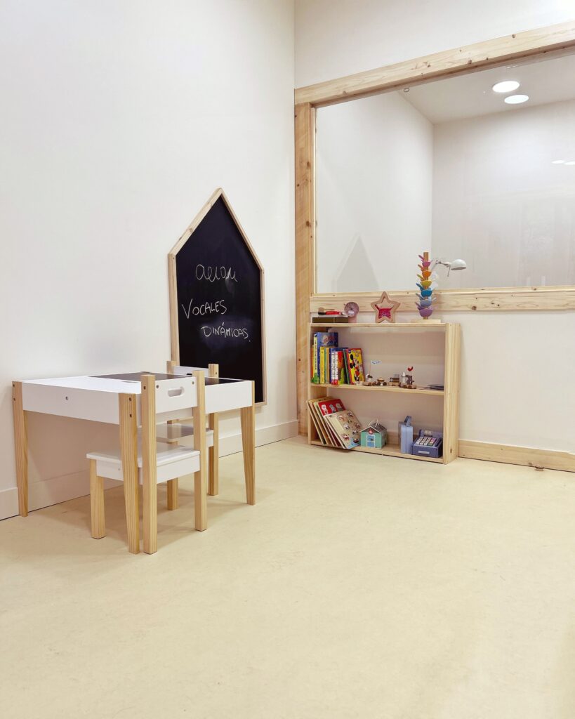 Espacio infantil de psicología con mesa, sillas pequeñas y pizarra para actividades
