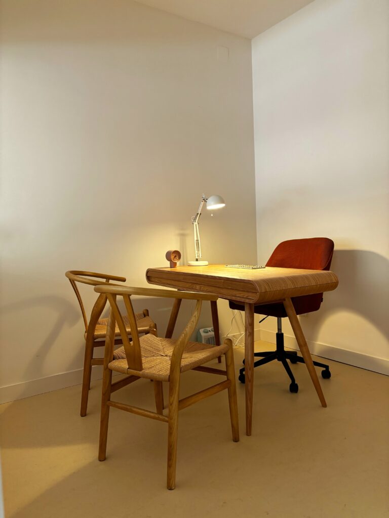Despacho de la clínica con mesa de trabajo y sillas de madera en un ambiente tranquilo